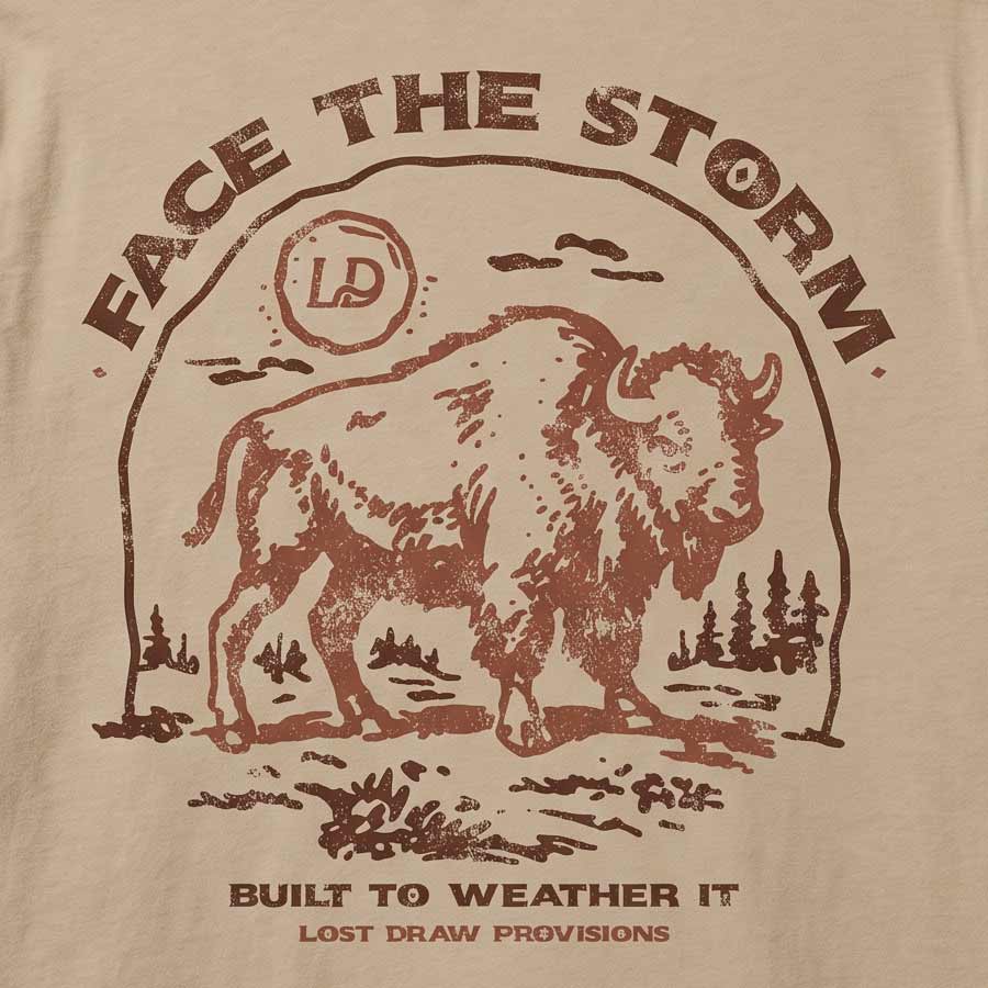 Close-up of a beige fabric surface with a distressed brown graphic print featuring a bison, the words “FACE THE STORM,” and smaller text reading “BUILT TO WEATHER IT” and “LOST DRAW PROVISIONS.”.