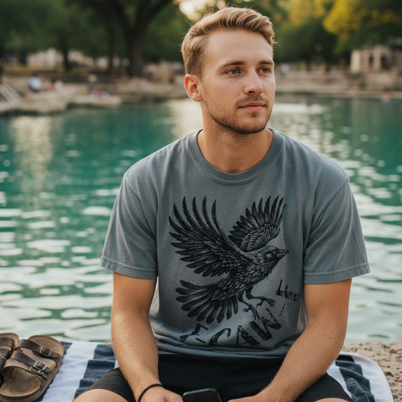 Man wearing a t-shirt with an eagle design by a lake