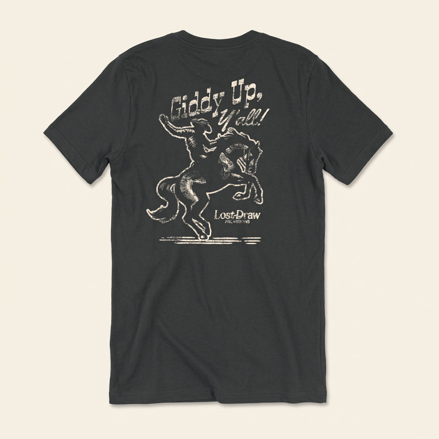 A dark charcoal gray t-shirt shown from the back, featuring a distressed white graphic of a cowboy riding a bucking horse with the text &