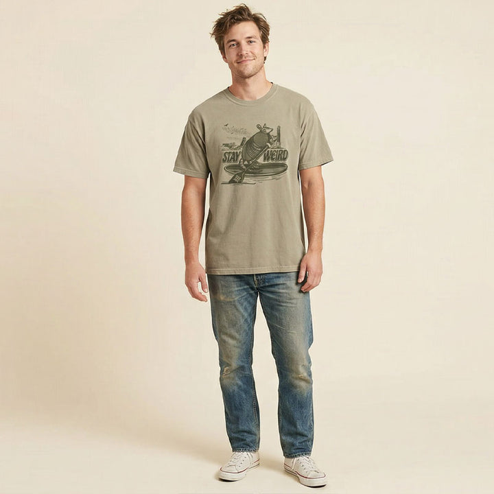 Man wearing a 512 Austin armadillo t-shirt with stay weird paddleboard graphic on khaki tee