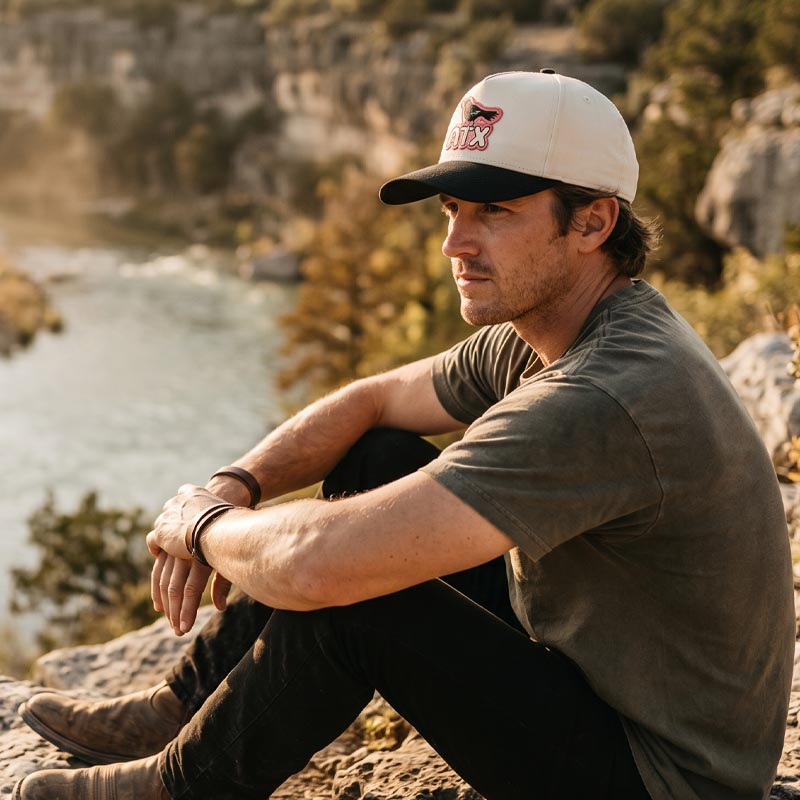 Person wearing ATX Perch Austin grackle hat outdoors during golden hour in Texas
