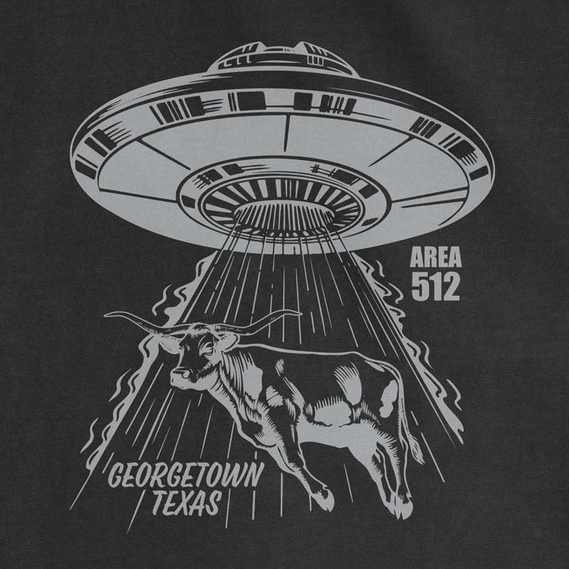 Close-up of the Georgetown Area 512 graphic featuring a UFO abducting a longhorn, printed with metallic silver ink on a black t-shirt.