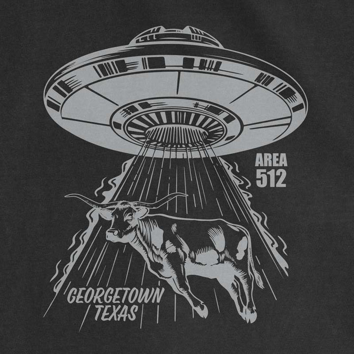 Close-up of the Georgetown Area 512 graphic featuring a UFO abducting a longhorn, printed with metallic silver ink on a black t-shirt.