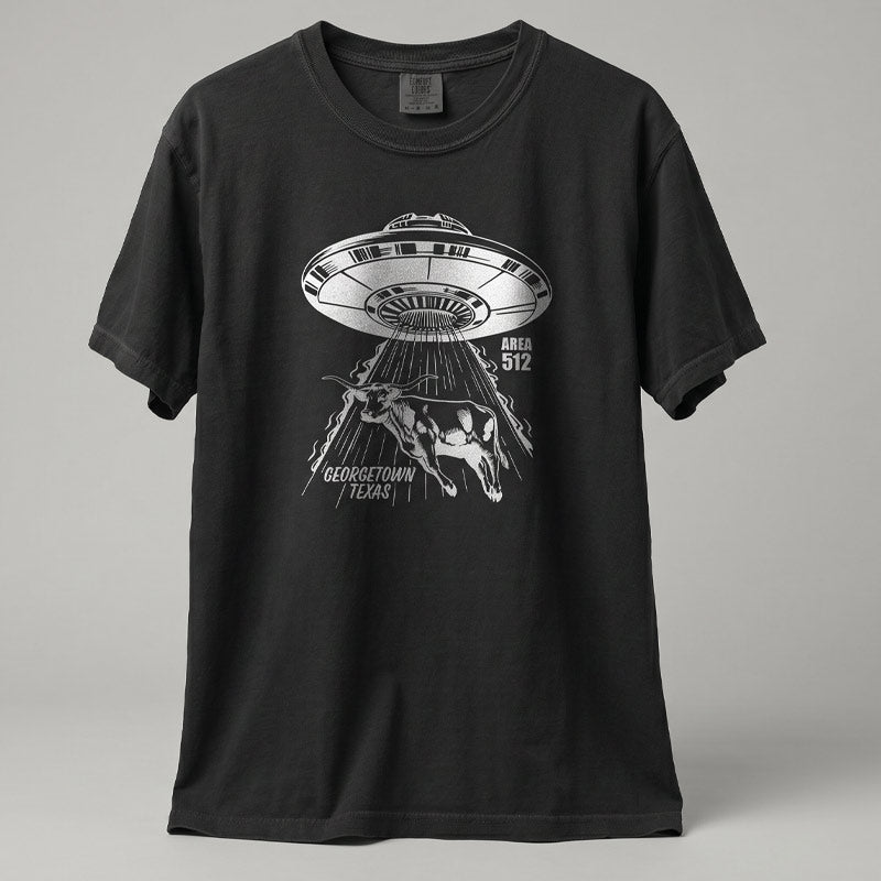 Black Comfort Colors heavyweight t-shirt with Georgetown Area 512 metallic silver UFO design displayed in studio setting.