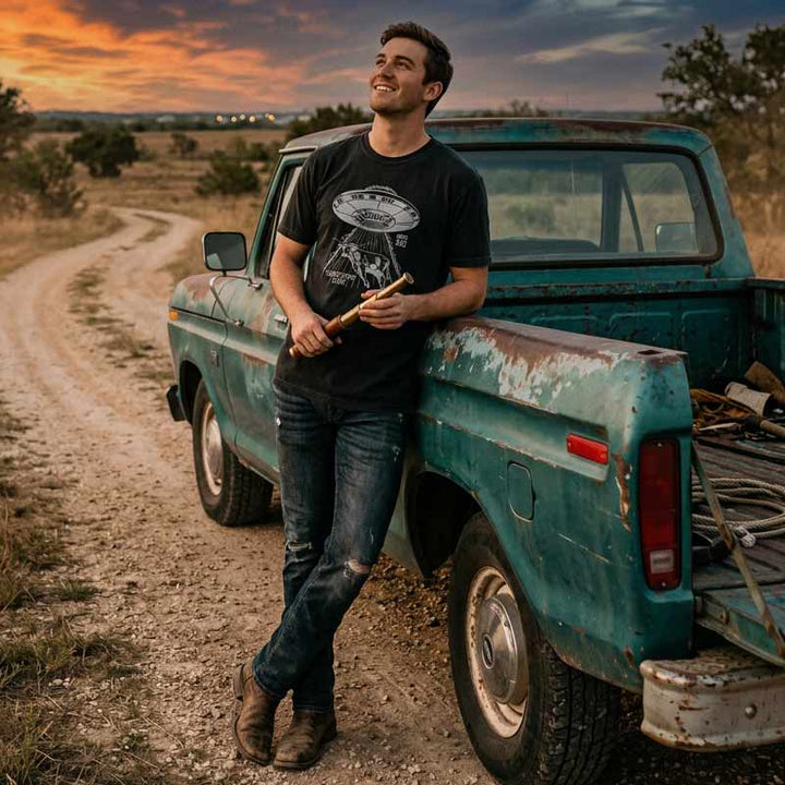 Man wearing the Georgetown Area 512 UFO longhorn t-shirt outdoors in a relaxed Texas setting at sunset.