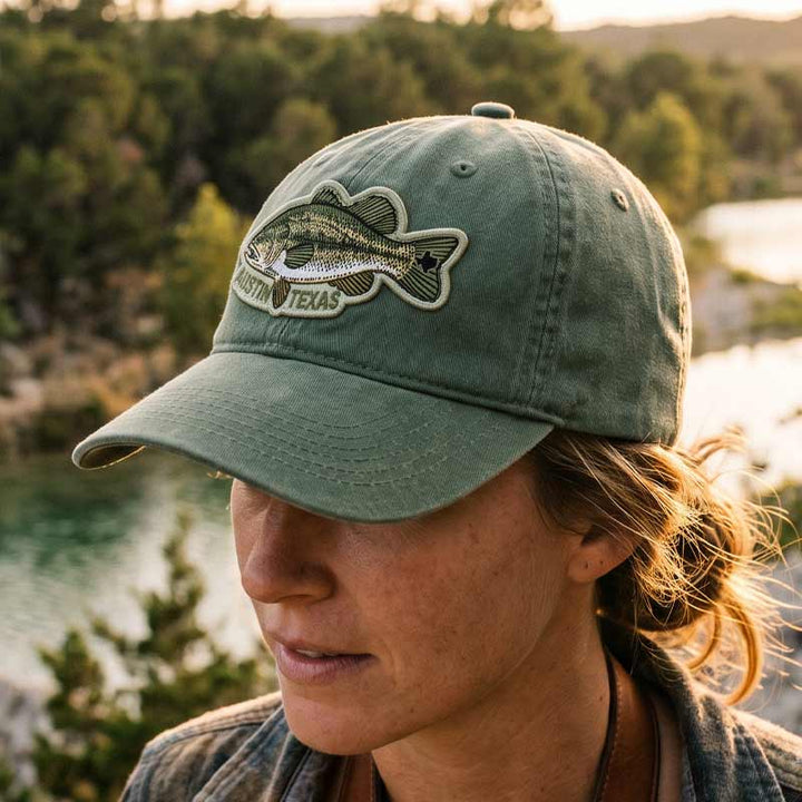 woman wearing ATX Bass Hat outdoors near a Texas lake
