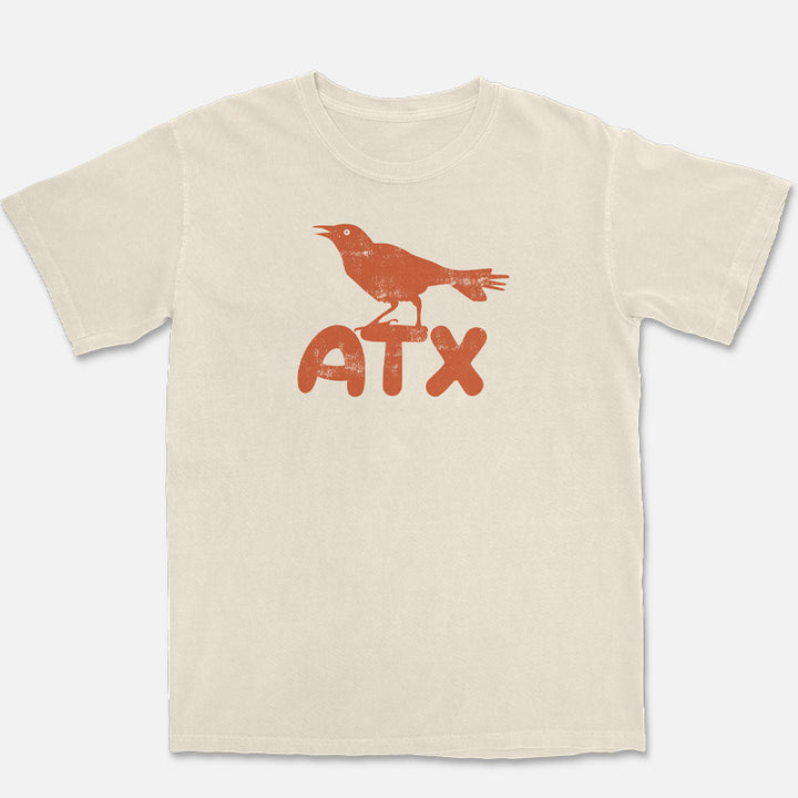 ATX Perch ivory t-shirt with orange grackle perched on ATX lettering flat lay