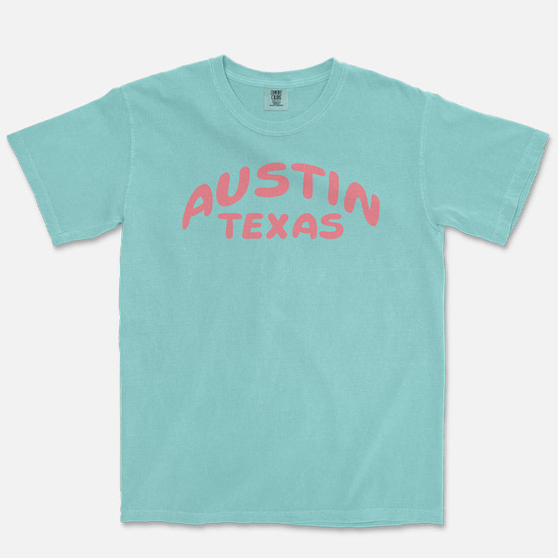 Front view of a Chalky Mint Comfort Colors 1717 heavyweight unisex t-shirt featuring a coral Austin Texas graphic across the chest.