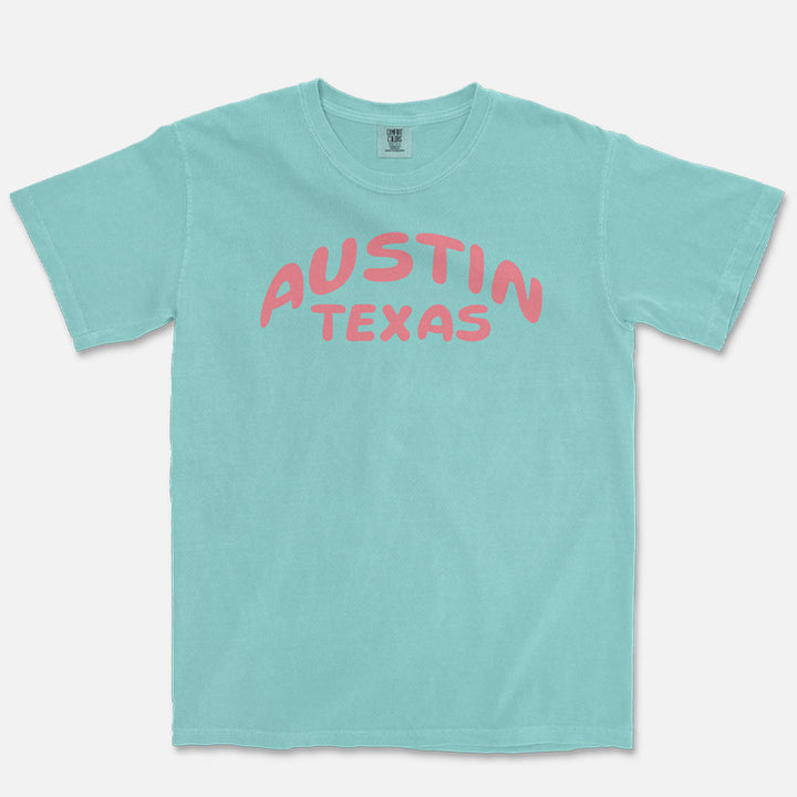 Front view of a Chalky Mint Comfort Colors 1717 heavyweight unisex t-shirt featuring a coral Austin Texas graphic across the chest.