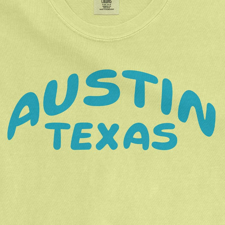 close up view of a Neon Lemon Comfort Colors 1717 heavyweight unisex t-shirt featuring an aqua blue Austin Texas graphic across the chest.