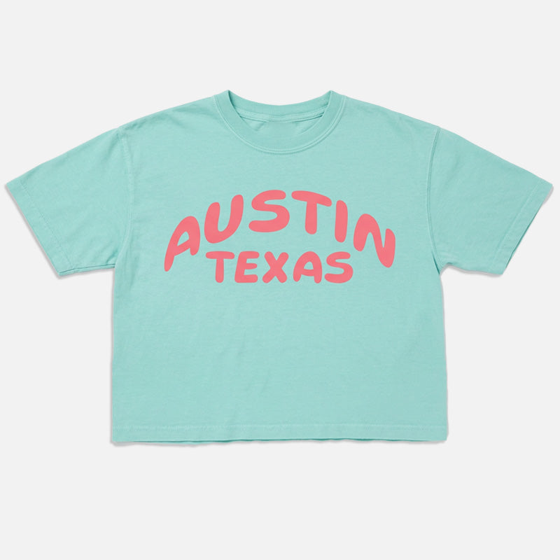 Flay lay of Austin Pop women’s boxy t-shirt in Chalky Mint with pink Austin Texas graphic