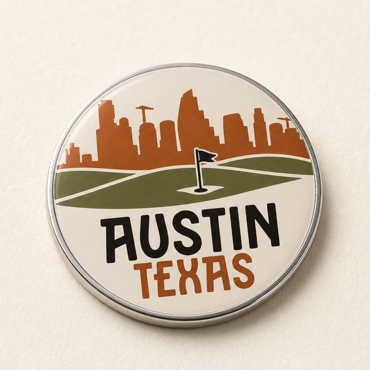 A round metal pinback badge featuring a stylized Austin Texas golf course and skyline design, with the words &