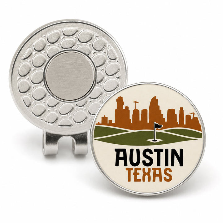 A silver metal golf ball marker set on a white background, showing both the back with a textured pattern and the front featuring an Austin Texas golf course design with a skyline, green hole, and text.