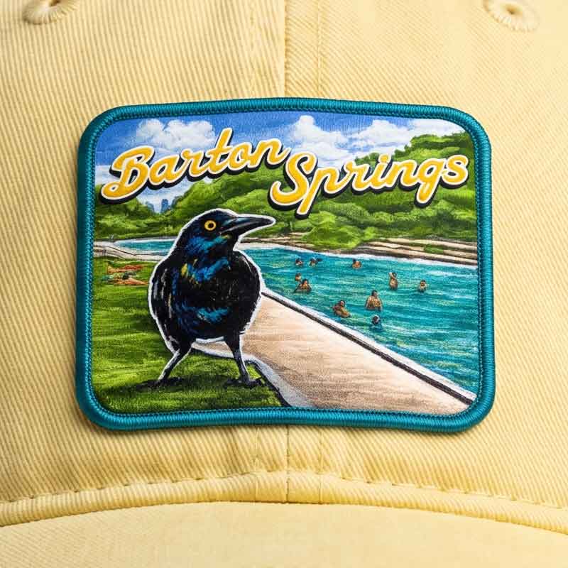 Close-up detail of Barton Springs UV printed patch featuring grackle artwork and spring pool scene