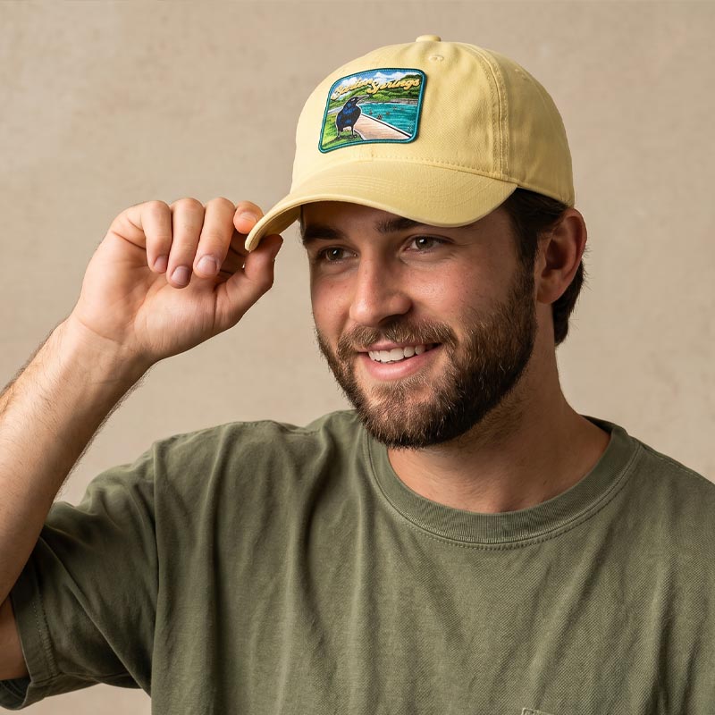 Person wearing Barton Springs hat outdoors in Austin Texas near water
