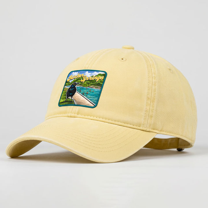 Butter-colored Barton Springs hat with UV printed patch featuring Austin grackle and Barton Springs pool scene