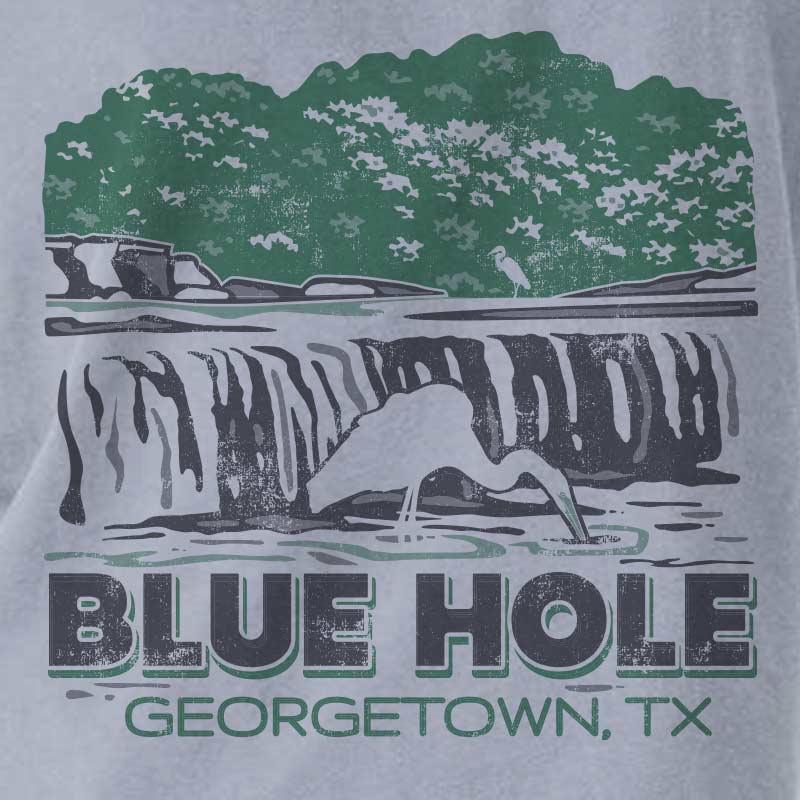 Close-up of Blue Hole Georgetown Texas waterfall graphic on a garment-dyed women’s boxy t-shirt with green and black distressed print