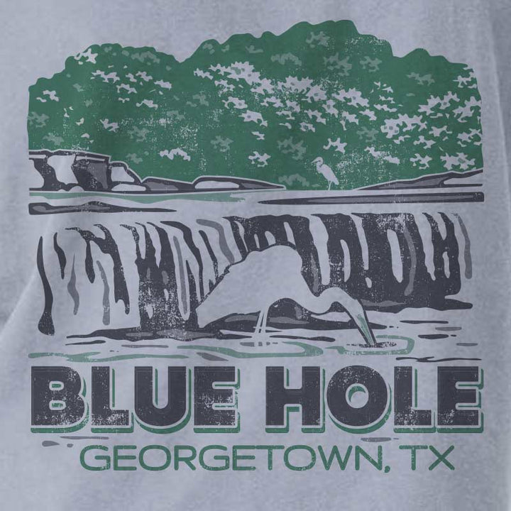 Close-up of Blue Hole Georgetown Texas waterfall graphic on a garment-dyed women’s boxy t-shirt with green and black distressed print