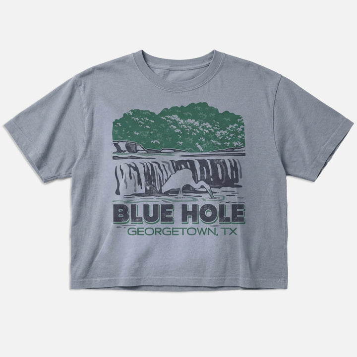 Flat lay of women’s boxy Blue Hole Georgetown TX t-shirt in garment-dyed grey with vintage waterfall design and relaxed cropped fit