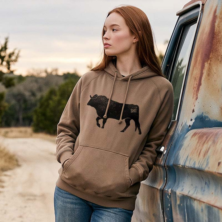 A woman with red hair wearing a brown hoodie with a black bull graphic and &