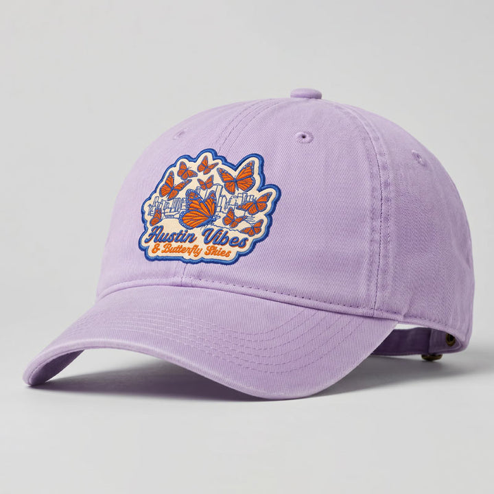 Orchid Butterfly Skies Hat featuring embroidered monarch butterfly patch and Austin skyline artwork
