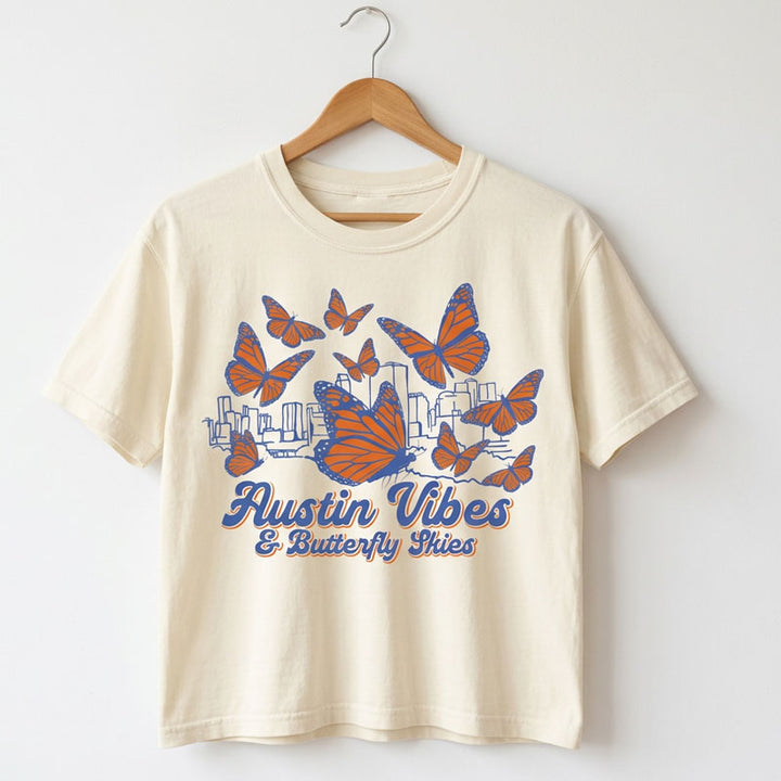Butterfly Skies women’s heavyweight t-shirt on a hanger.