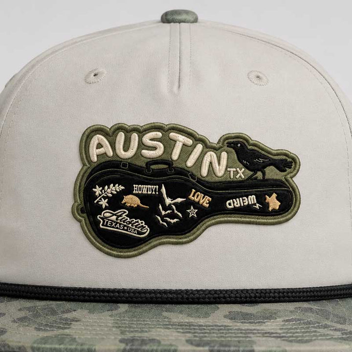Close-up detail of the Austin guitar case artwork patch on the Carry-On Austin Camo Hat
