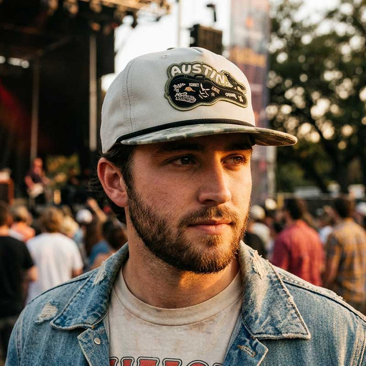 Man wearing the Carry-On Austin Camo Hat at an outdoor Austin concert
