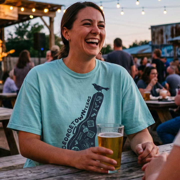 Woman in a blue t-shirt holding a beer at an outdoor event