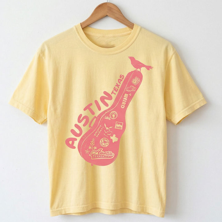 Women’s garment-dyed boxy tee in butter with Austin travel graphic on a hanger against a white background
