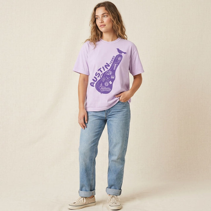 Person wearing a light purple t-shirt with a graphic design on a beige background