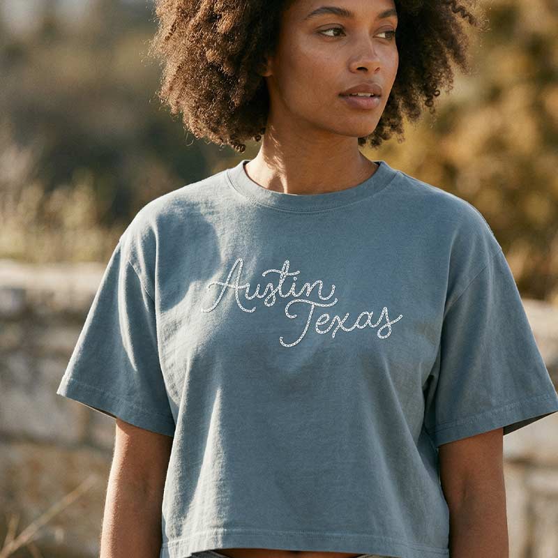Woman wearing blue Chainstitch Austin boxy t-shirt with script design