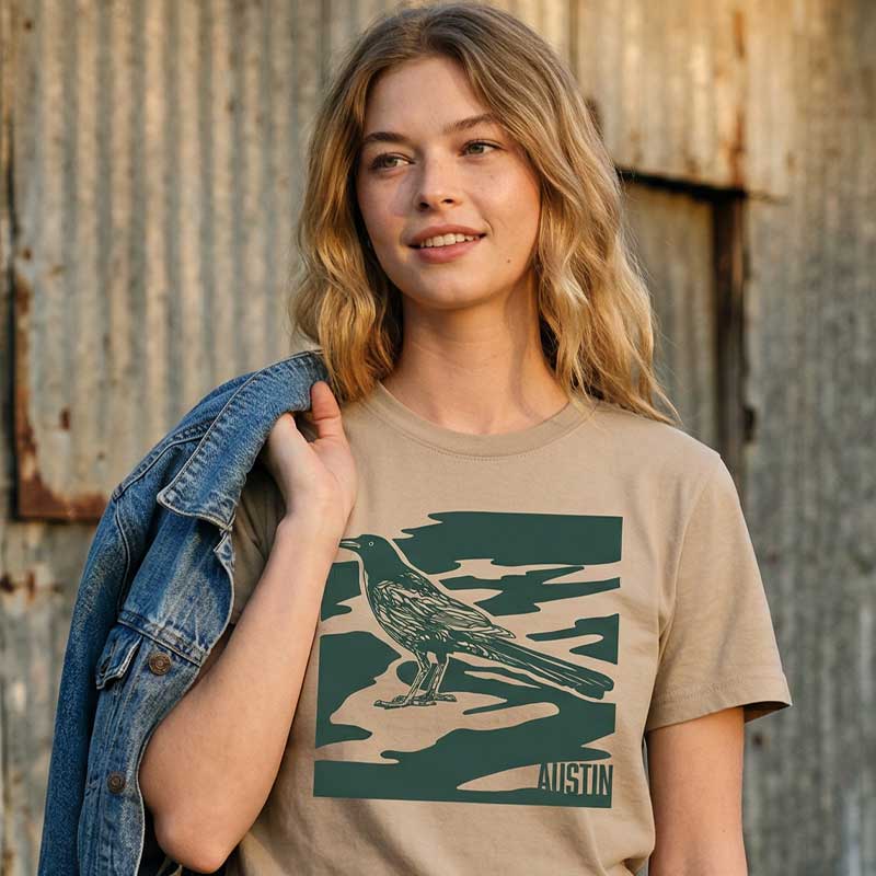 Woman wearing khaki garment-dyed City Camo Austin boxy t-shirt with bird graphic