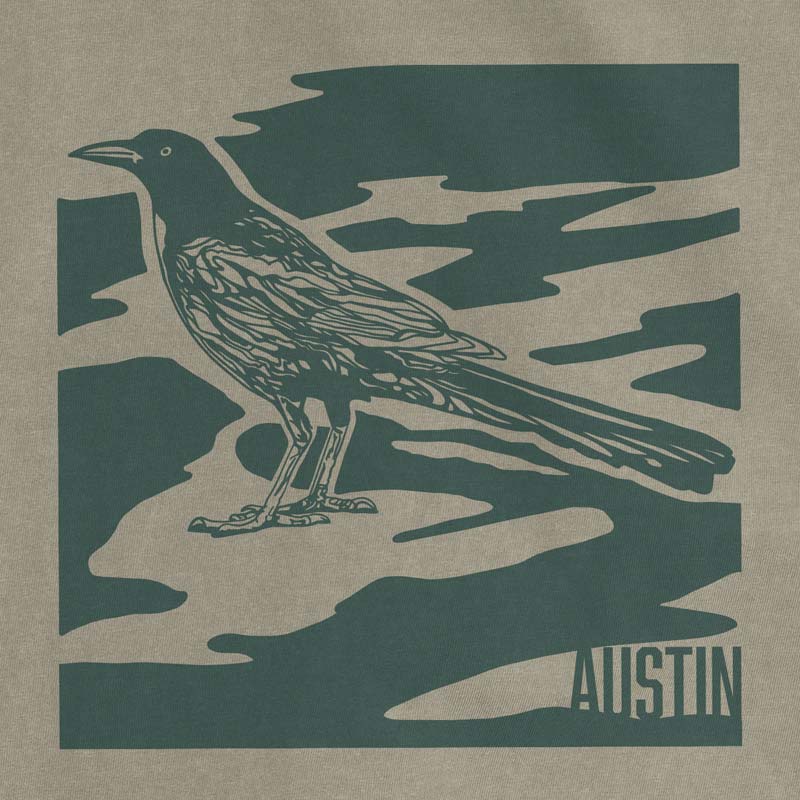 Close-up of tonal green grackle illustration on garment-dyed t-shirt