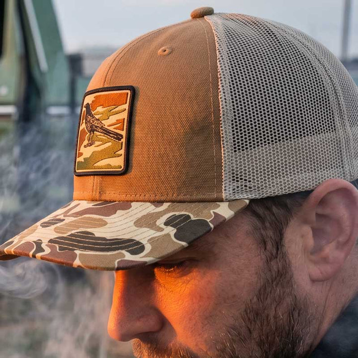 close up profile of Saddle and duck camo DRI DUCK trucker hat with UV printed grackle camouflage patch designed to look embroidered