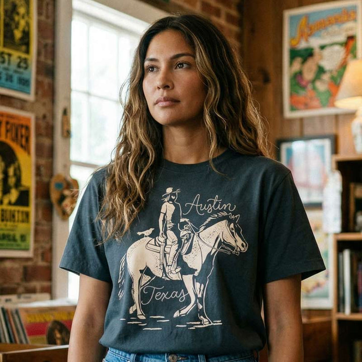 Woman wearing washed black Dust & Reins Austin boxy t-shirt with western rider graphic
