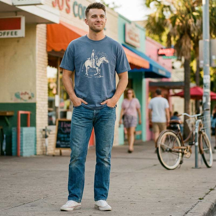Man wearing a Vintage style Austin graphic tee in denim blue, surrounded by a street scene.