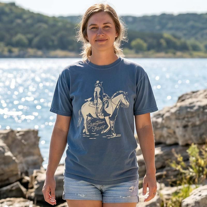 Woman wearing a Dust and Reins Georgetown Texas T-shirt on Comfort Colors 1717 by a lake