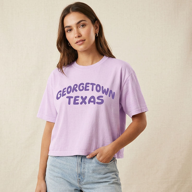 Woman wearing Orchid women’s boxy t-shirt with purple Georgetown Texas retro style graphic