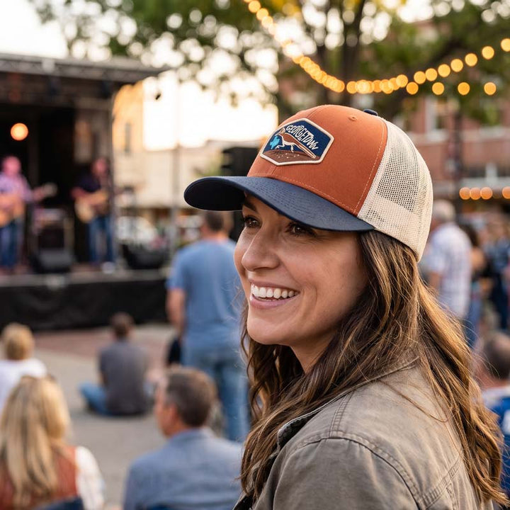 Woman wearing the Georgetown Road Runner trucker hat, smiling at an outdoor event.