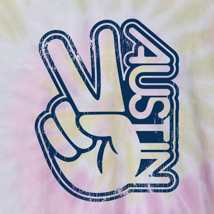 Desert Rose tie-dye t-shirt with warm pink, cream, and golden tones featuring a vintage-style navy Austin peace sign graphic printed on the front of a relaxed unisex tee.