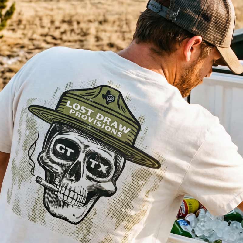 Man outdoors wearing GTX Ranger oversized tee in dirty white featuring large Lost Draw Provisions ranger skull back graphic.