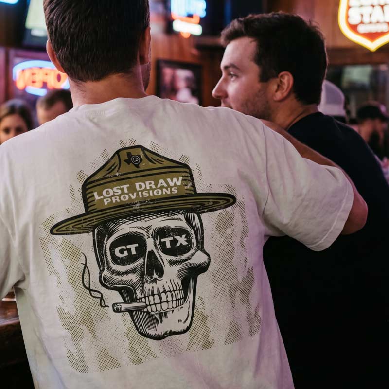 Lifestyle photo of person wearing GTX Ranger oversized tee at a bar featuring large Lost Draw ranger skull graphic on the back.