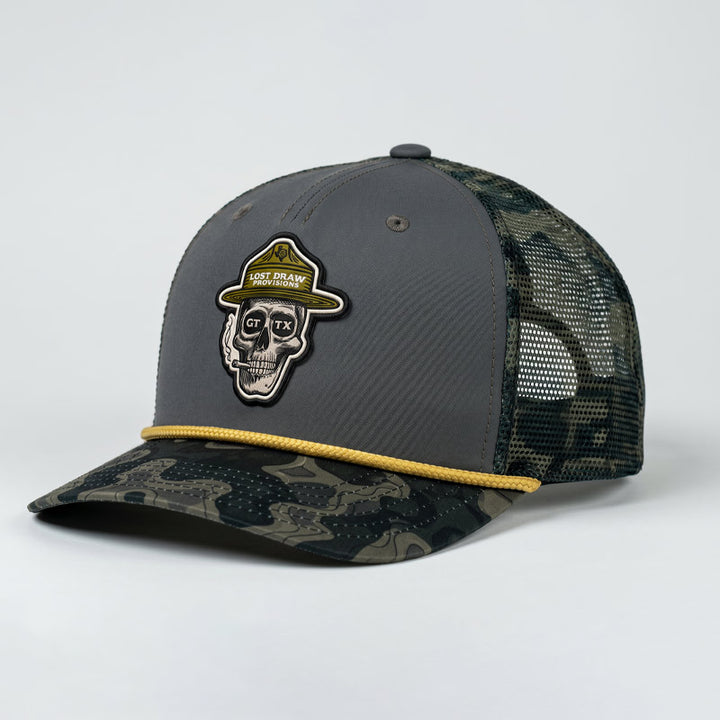 GTX Ranger Hat by Lost Draw Provisions on a Sobro Goods 5-panel trucker in Thermal Hog / Darkwood. Features a skull ranger patch with GTX sunglasses, topo camo bill, gold rope detail, and breathable mesh back.