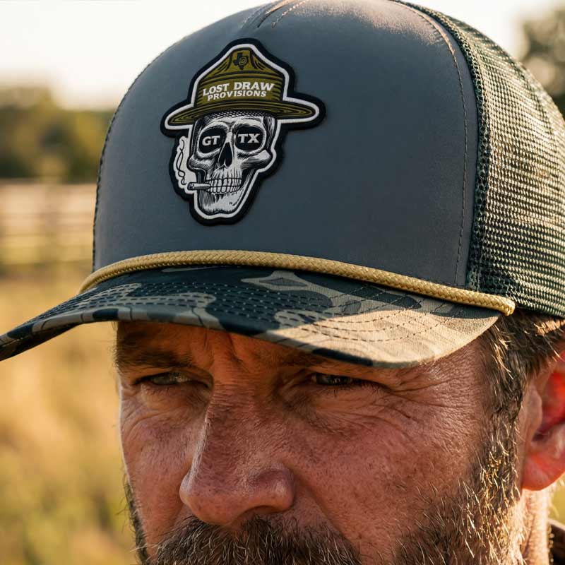 Close-up portrait of a man wearing the GTX Ranger Hat outdoors. Detailed skull ranger patch, camo brim, and rugged western-outdoor styling in warm evening light.