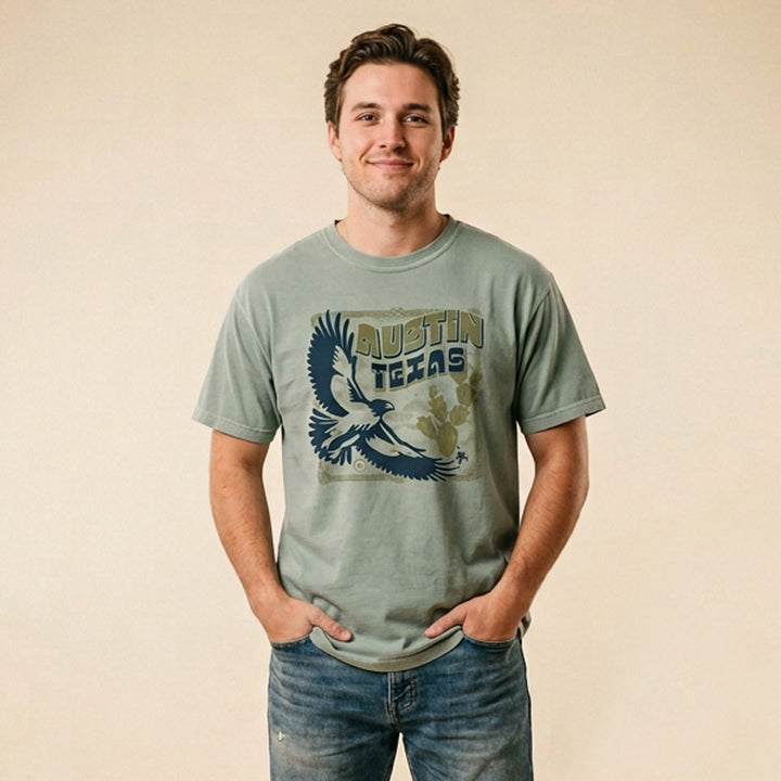 Man wearing a Bay green unisex t-shirt with hawk, cactus, and scorpion graphic
