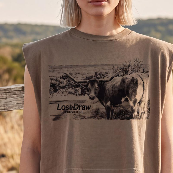 A woman wearing a sleeveless tan t-shirt with a black and white graphic of a longhorn steer and the text &