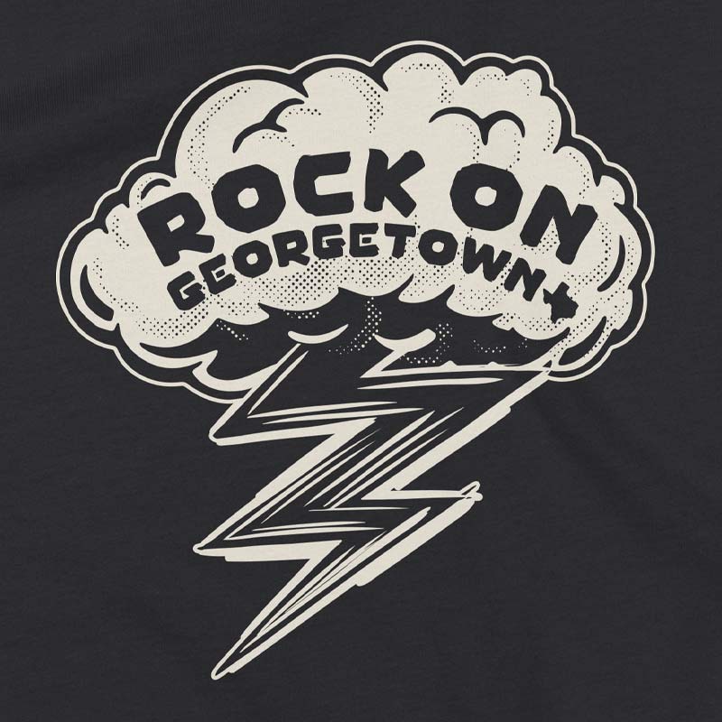 Close-up of the Rock On Georgetown youth shirt graphic featuring bold lettering, lightning bolt artwork, and vintage distressed detailing on dark grey fabric.