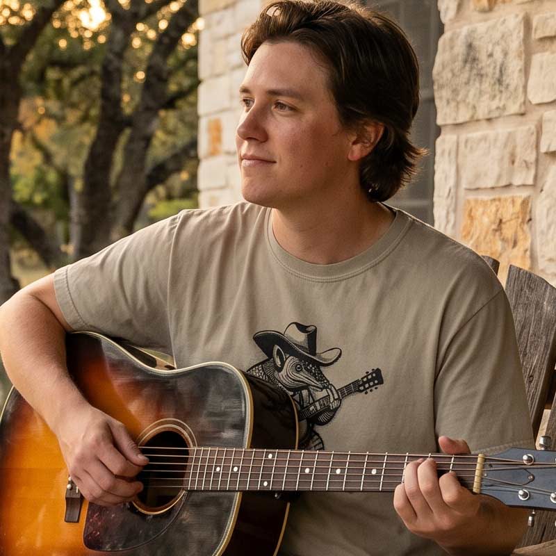 Man wearing Rockin Armadillo t-shirt playing acoustic guitar on a rustic Texas front porch
