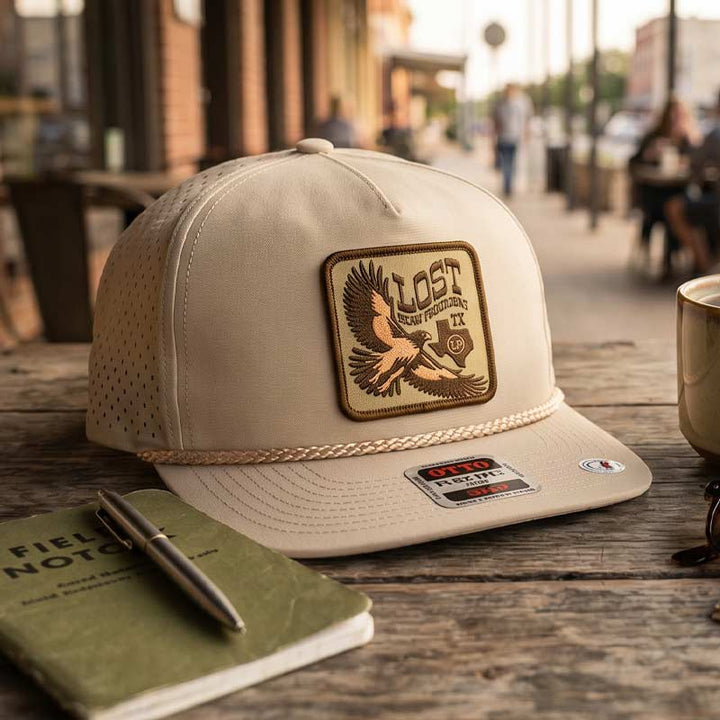 Beige cap with a logo on a wooden surface with a notebook and pen.